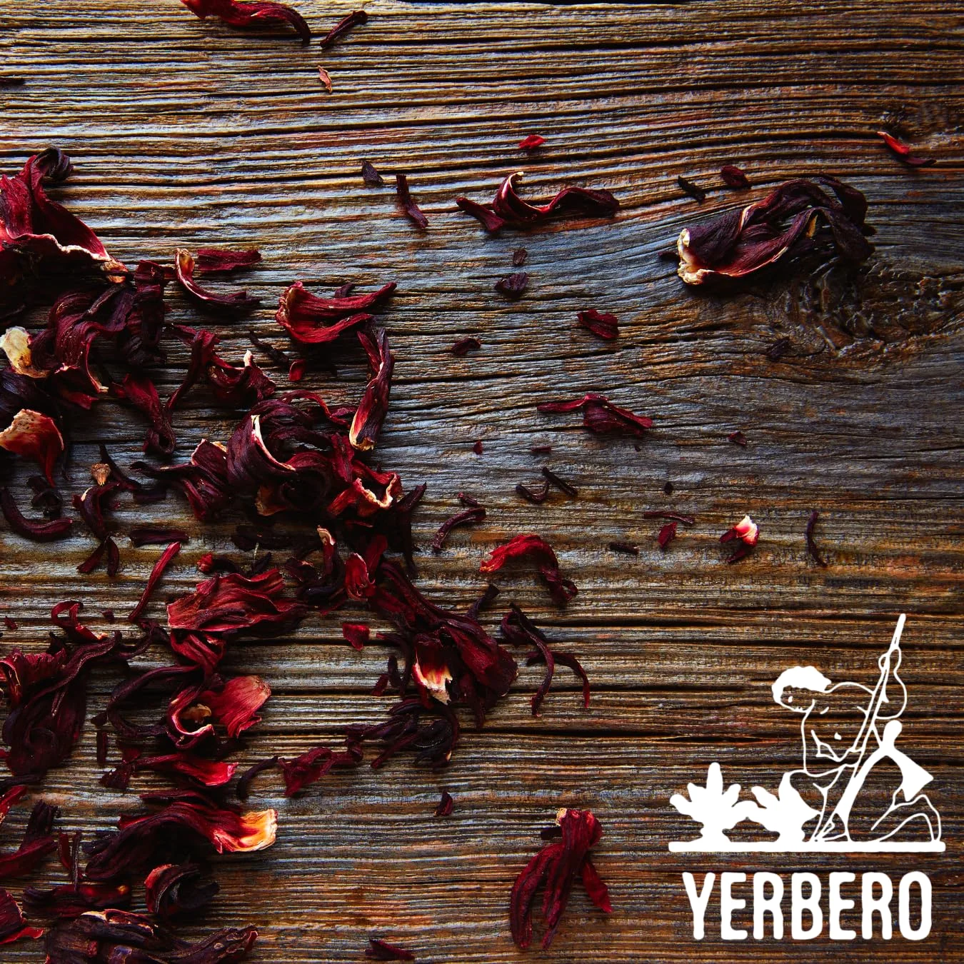 Dried dark red hibiscus calyces scattered across a weathered wooden table